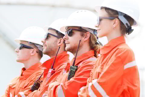 Engineers in safety suits in front of storage tanks